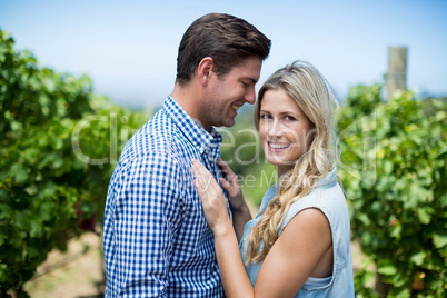 Side view of happy young couple embracing at vineyard