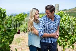 Smiling couple embracing at vineyard