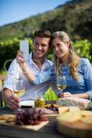 Happy couple taking selfie with wineglasses at table