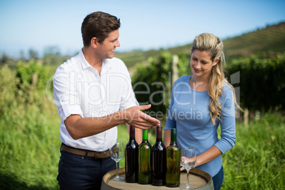 Happy friends standing by wine bottles on berrel