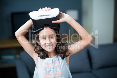 Portrait of girl holding virtual reality headset in living room
