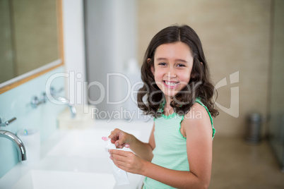 Girl putting toothpaste on brush in bathroom