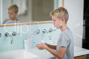 Boy putting toothpaste on brush in bathroom