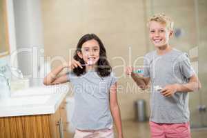 Siblings brushing their teeth in bathroom