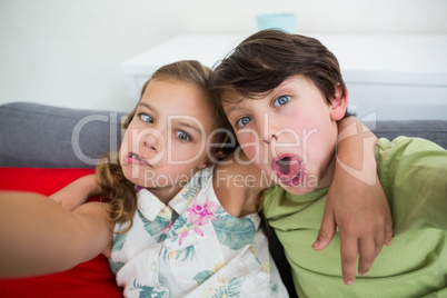 Siblings pulling funny faces in living room