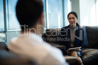 Businesswoman discussing with male colleague while holding digital tablet
