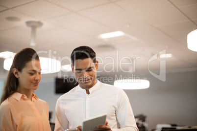 Businessman showing digital tablet to female colleague