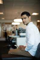 Portrait of businessman holding mobile phone at office