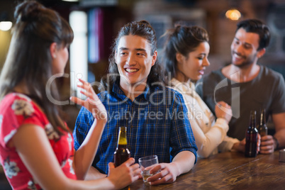 Happy friends interacting at bar counter