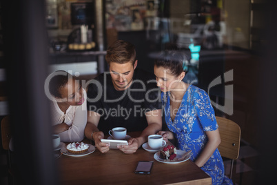 Friends using digital tablet while having breakfast