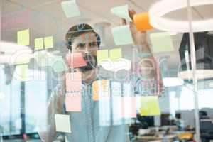 Businessman analyzing stratedy on glass while using mobile phone