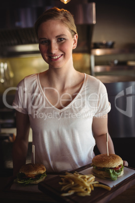 Beautiful woman holding burger and french fries in a tray at restaurant