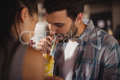 Close-up of couple having milkshake