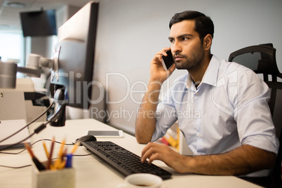 Businessman using mobile phone and computer in office