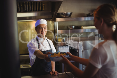Chef passing tray with french fries to waitress
