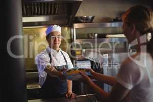 Chef passing tray with french fries to waitress