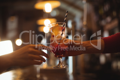 Female bar tender giving glass of cocktail to customer