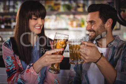 Happy couple toasting glasses of beer at counter