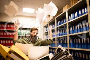 Irritated businessman throwing papers in file storage room