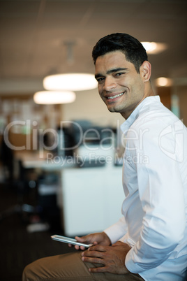 Portrait of smiling businessman holding mobile phone