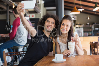 Happy couple taking selfie while sitting in restaurant