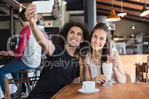 Happy couple taking selfie while sitting in restaurant