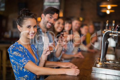 Happy young friends holding short glasses at counter