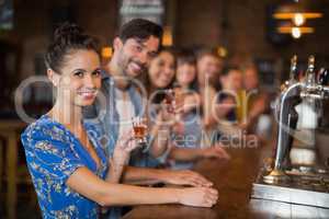 Happy young friends holding short glasses at counter