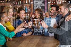Cheerful friends toasting beer glasses and bottles