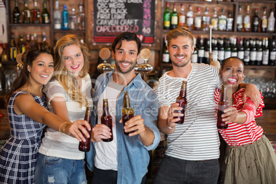 Cheerful friends holding beer bottles at pub