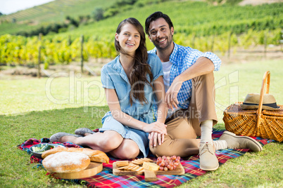 Portrait of happy couple sitting on picnic blanket