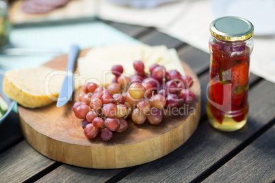 Grapes with cheese by jar on wooden table