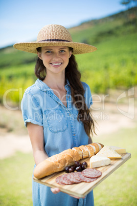 Portrait of woman holding bread with cheese and meat on wooden tray