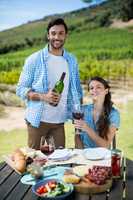 Portrait of happy couple holding red wine bottle and glass