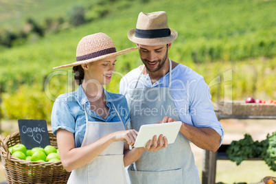 Happy couple using digital tablet at farm