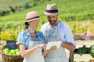 Happy couple using digital tablet at farm