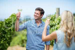 Young couple raising hands while holding wineglasses