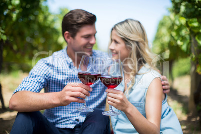 Couple with wineglasses embracing at vineyard