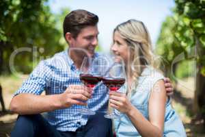 Couple with wineglasses embracing at vineyard