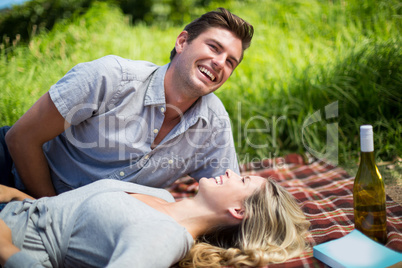Cheerful young couple enjoying while lying on blanket