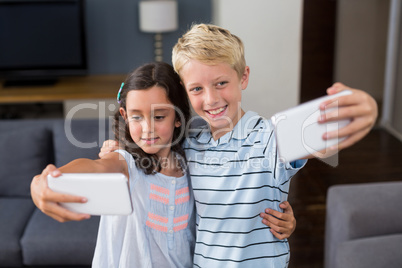 Siblings taking selfie on their mobile phone in living room