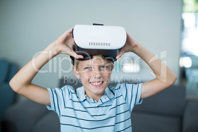 Portrait of boy holding virtual reality headset in living room