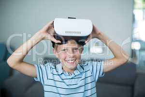 Portrait of boy holding virtual reality headset in living room