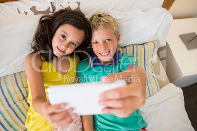 Siblings taking selfie on mobile phone in bedroom