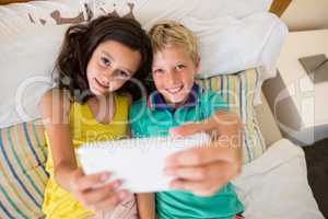 Siblings taking selfie on mobile phone in bedroom