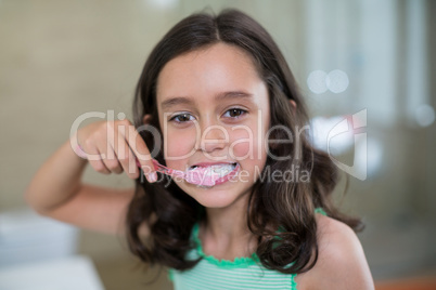Portrait of smiling girl brushing her teeth in bathroom