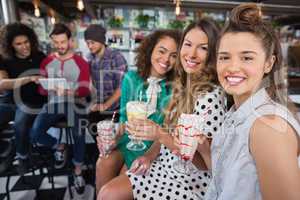 Female friends having drink while male friends using digital tablet in restaurant