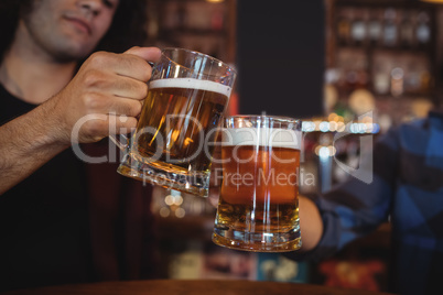 Two young men toasting their beer mugs