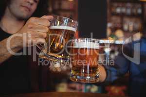 Two young men toasting their beer mugs