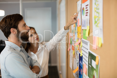 Young businessman with female colleague analyzing charts at office